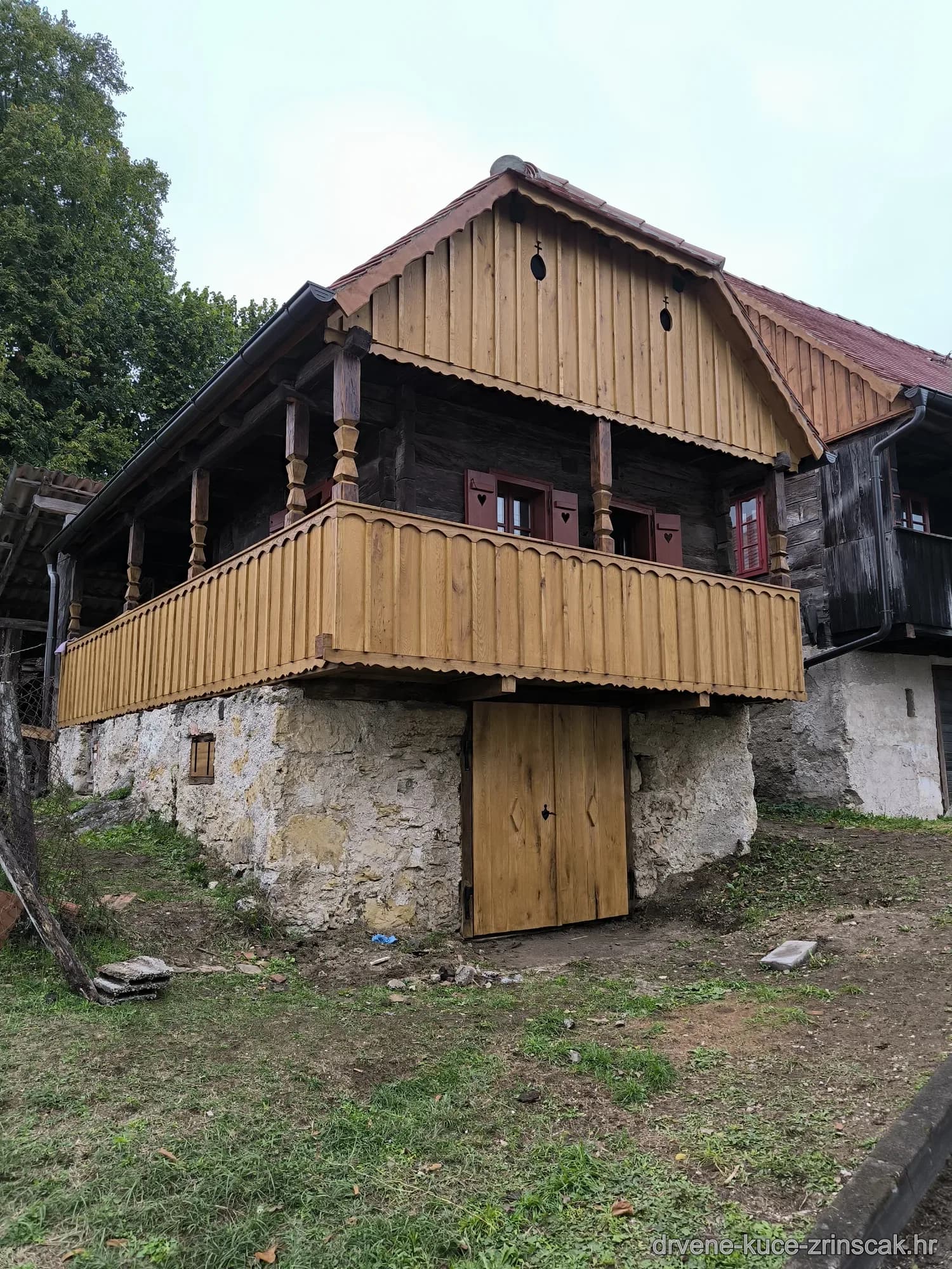 Drvena kuća s balkonom na kamenoj bazi (bočni pogled)