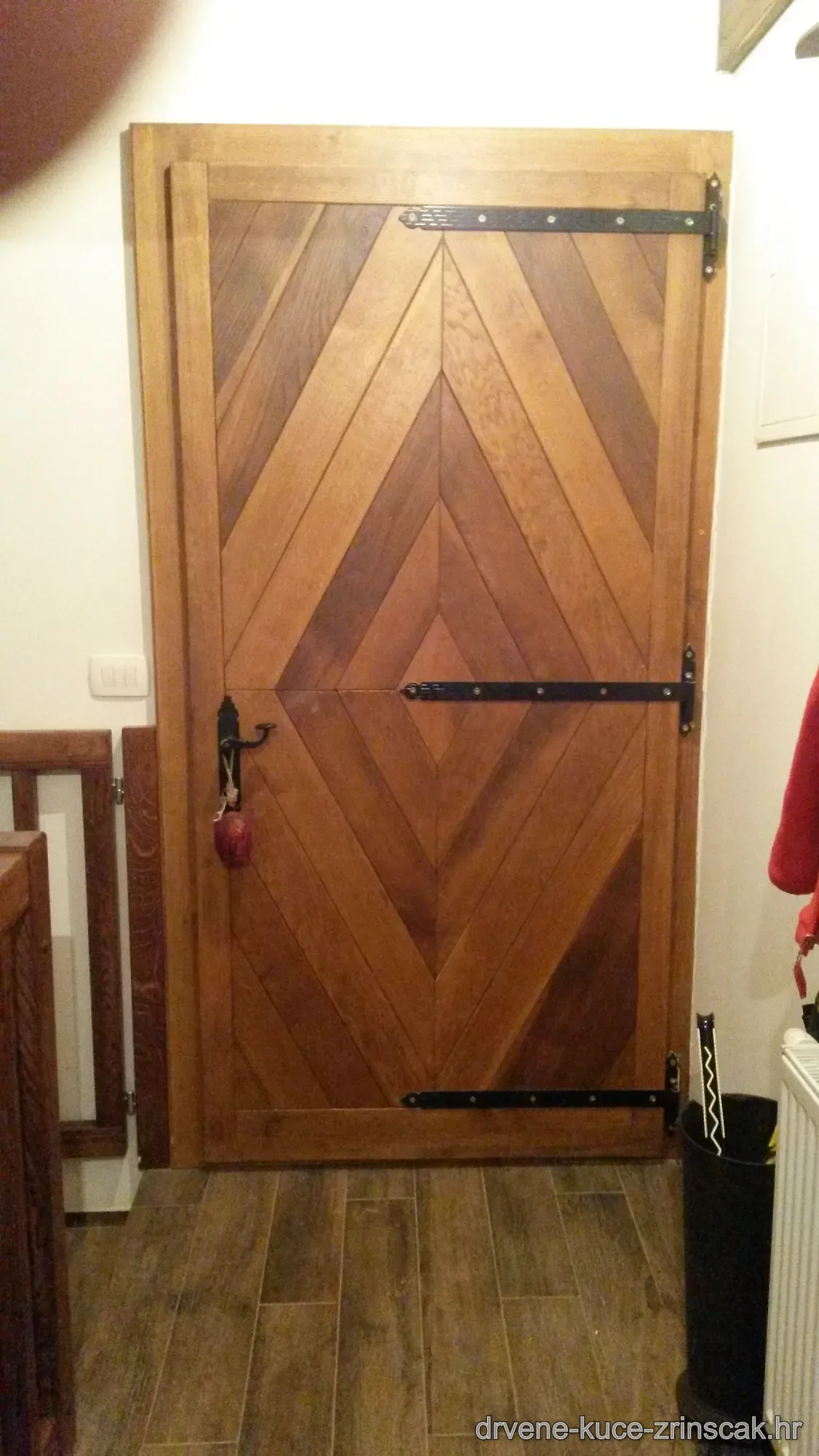 Unutarnja masivna drvena vrata s chevron uzorkom i crnim okovom